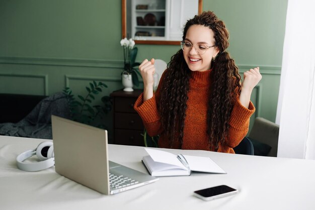 Donna felice che vince online ricevendo buone notizie via e-mail sul laptop eccitato studente che festeggia