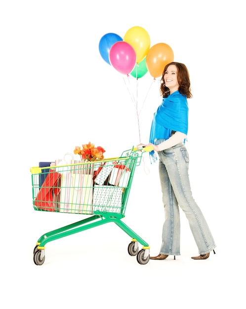 donna felice con carrello e palloncini sul muro bianco