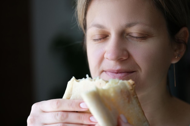 Donna felice con gli occhi chiusi che tiene pane bianco che cucina delizioso pane fresco a casa concetto