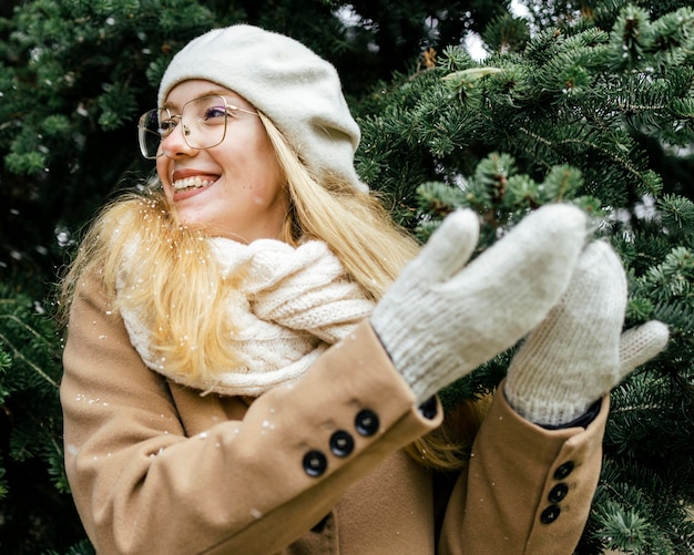 Donna felice con guanti godendo la nevicata al parco in inverno