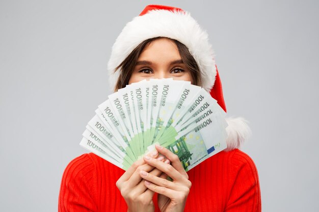 donna felice con il cappello di Babbo Natale con i soldi a Natale