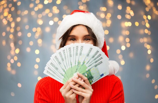 donna felice con il cappello di Babbo Natale con i soldi a Natale