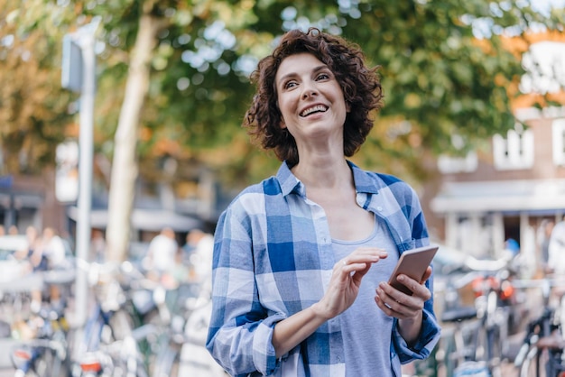 Donna felice con il cellulare in città