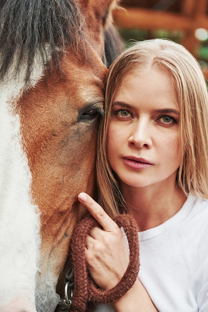 Donna felice con il suo cavallo nel ranch durante il giorno.