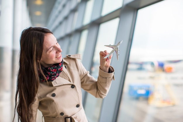 Donna felice con l'aeroplano di piccolo modello dentro l'aeroporto