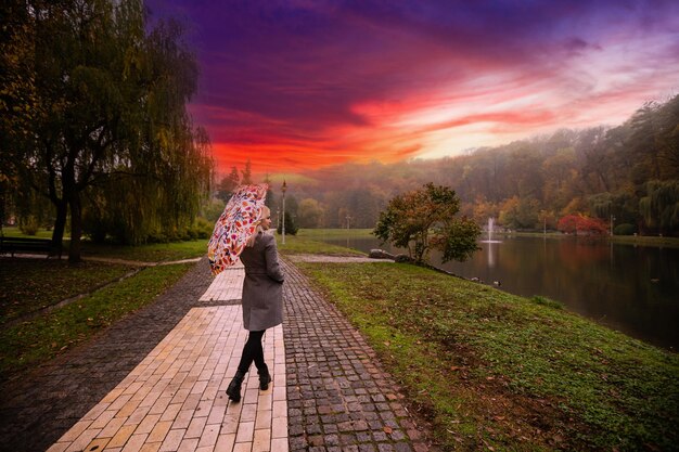 Donna felice con l'ombrello nel parco d'autunno