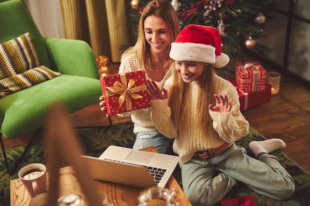 Donna felice con la figlia che celebra il Natale con i parenti online