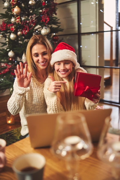 Donna felice con la figlia che comunica con i parenti online a Natale