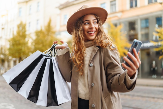 Donna felice con le borse della spesa che cammina per strada Acquisti sconti Black Friday concetto di vendita