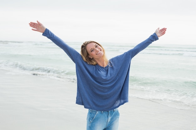 Donna felice con le mani sollevate in spiaggia