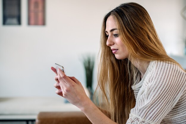 Donna felice con lo smartphone sul divano