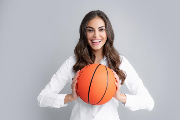 Donna felice con palla da basket isolata su sfondo grigio