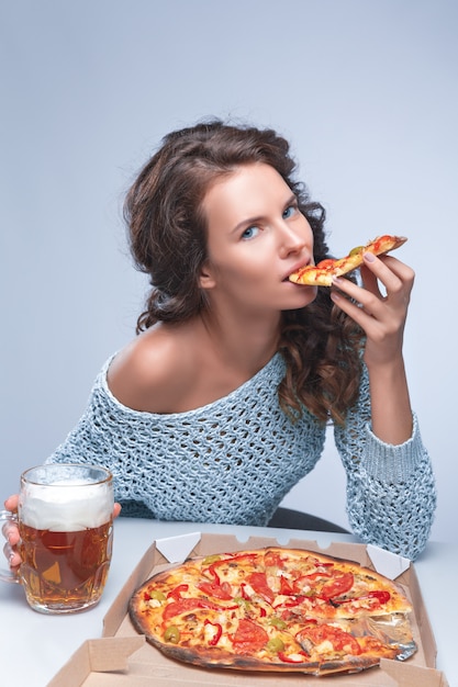 Donna felice con pizza e birra su spazio grigio, spazio per testo