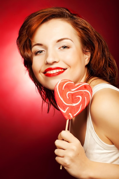 Donna felice con pop lecca lecca di caramelle cuore