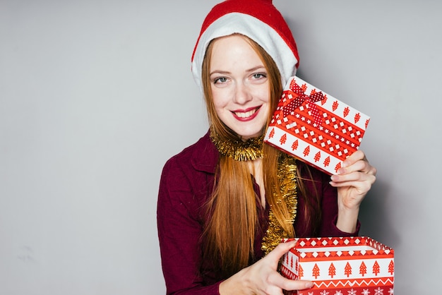 Donna felice con un cappello di Natale che tiene in mano dei regali