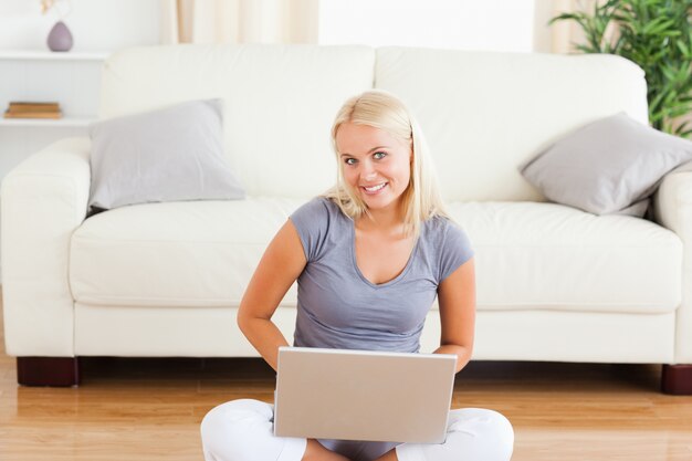 Donna felice con un notebook mentre era seduto sul pavimento