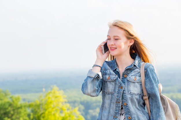 Donna felice con un sorriso che parla al telefono mentre si cammina nel parco