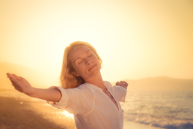 donna felice contro il tramonto con lo sfondo del mare