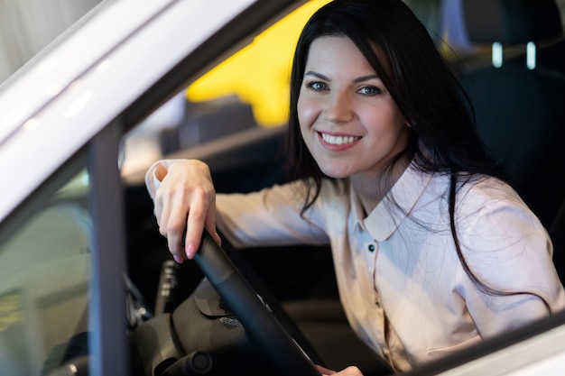 Donna felice del cliente che compra una nuova automobile nel centro di dealeship