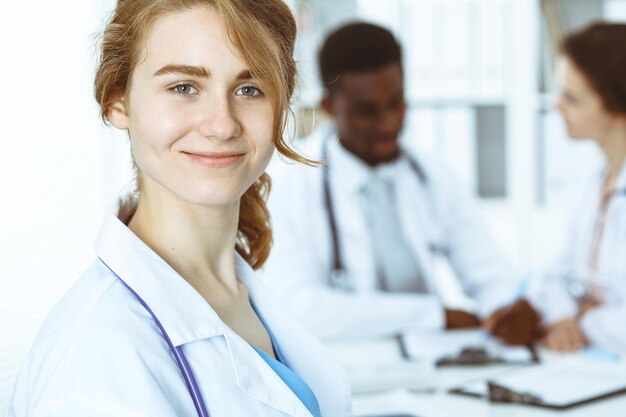 Donna felice del medico con il personale medico all'ospedale. Gruppo di persone multietniche.