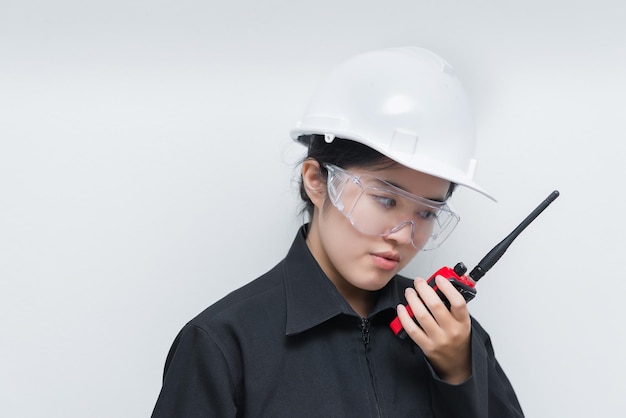 Donna felice dell'ingegnere asiatico che indossa occhiali che usa la comunicazione radio su sfondo bianco Il tecnico della Thailandia usa il walkie-talkie per lavoro