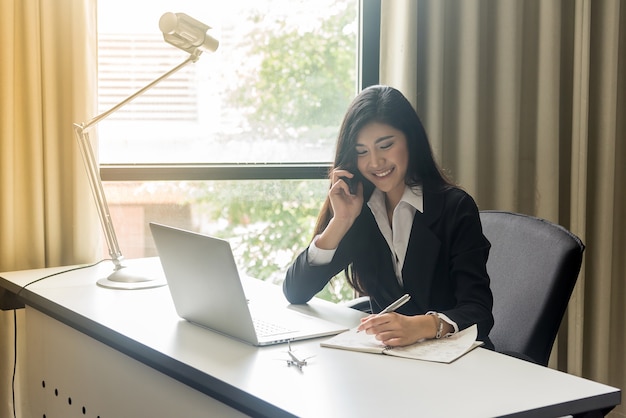 Donna felice di affari che parla sul telefono in ufficio