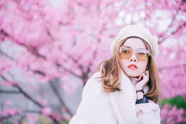 Donna felice e sorriso di viaggio con l'albero dei fiori di ciliegia di sakura sulla vacanza mentre molla, asiatica