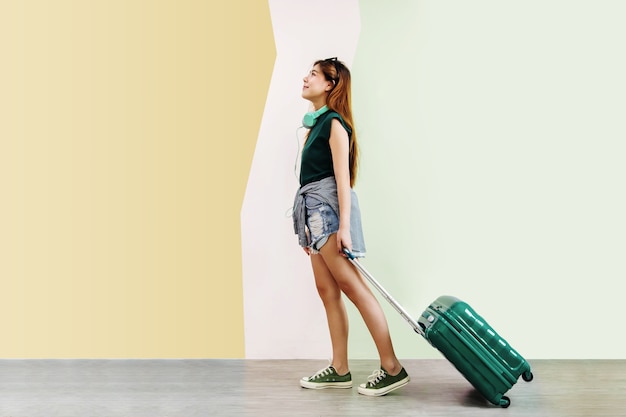 Donna felice giovane viaggiatore camminando con valigia e musica cuffie