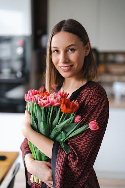 Donna felice godere bouquet di tulipani Casalinga godendo di un mazzo di fiori e interni della cucina Sweet home Senza allergie