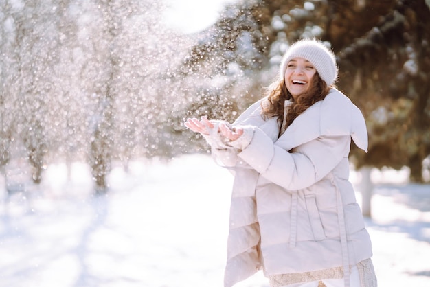 Donna felice in abiti in stile invernale che cammina nel parco innevato Concetto di viaggio per le vacanze nella natura