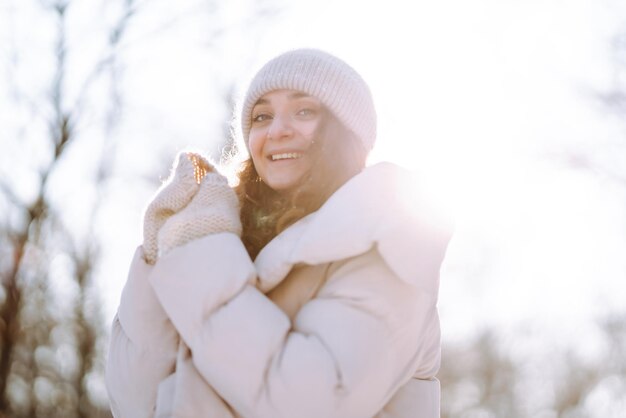 Donna felice in abiti in stile invernale che cammina nel parco innevato Concetto di viaggio per le vacanze nella natura