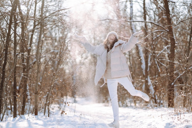 Donna felice in abiti in stile invernale che cammina nel parco innevato Concetto di viaggio per le vacanze nella natura