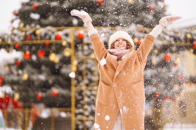 Donna felice in abiti in stile invernale sullo sfondo delle luci della ghirlanda Vacanze moda invernali