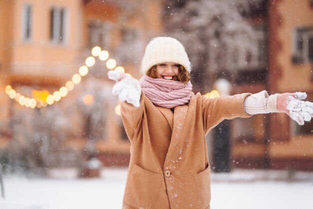 Donna felice in abiti in stile invernale sullo sfondo delle luci della ghirlanda Vacanze moda invernali