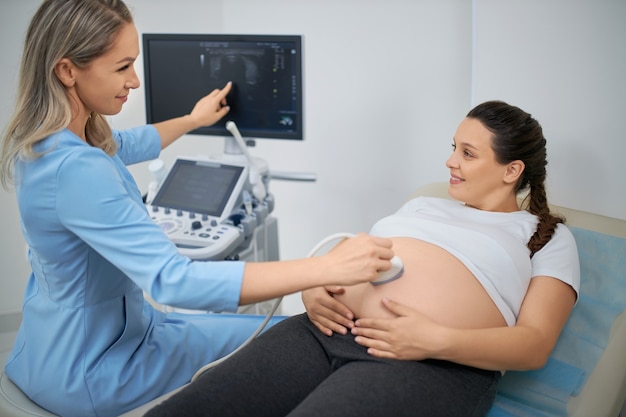 Donna felice in attesa che frequenta la clinica medica per l'ecografia