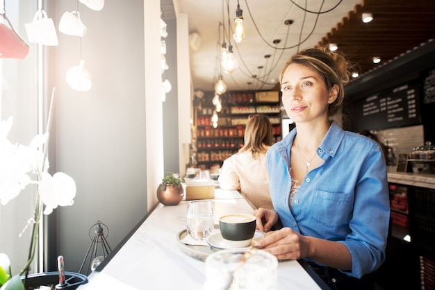 Donna felice in camicia blu in una caffetteria