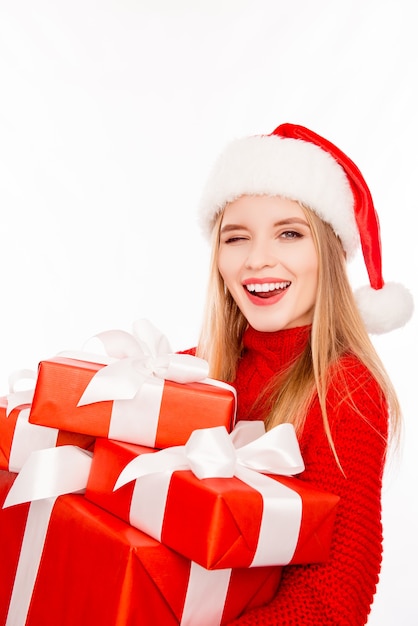 Donna felice in cappello della Santa che tiene i regali di natale e ammiccante