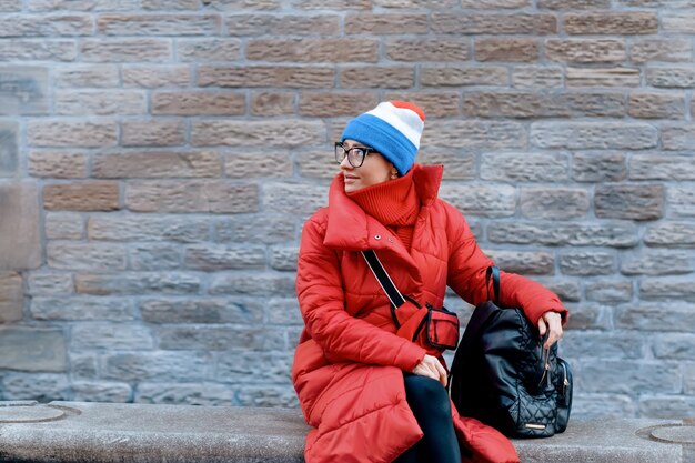 Donna felice in cappotto rosso, cappello in giro per la città quando fa freddo