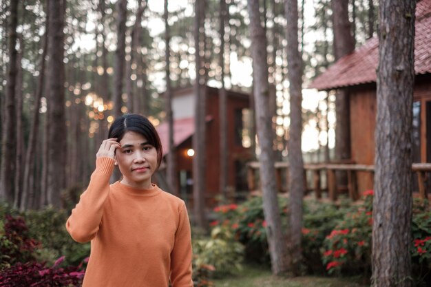 Donna felice in maglione che viaggia nella foresta di pini, visita turistica a Doi Bo Luang, Chiang Mai, Thailandia, punto di riferimento e popolare per le attrazioni turistiche. Concetto di vacanza e viaggio
