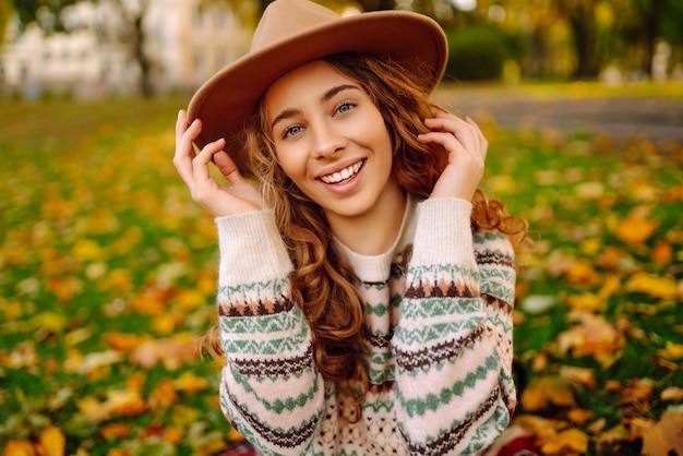 Donna felice in maglione elegante e cappello all'aperto nel parco autunnale su plaid La donna ama la natura autunnale