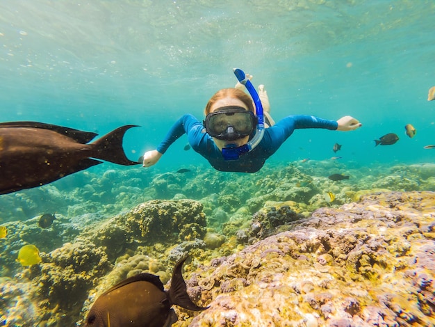 Donna felice in maschera per lo snorkeling immersioni subacquee con pesci tropicali nella barriera corallina piscina sul mare Stile di vita di viaggio sport acquatici avventura all'aperto lezioni di nuoto durante le vacanze estive al mare