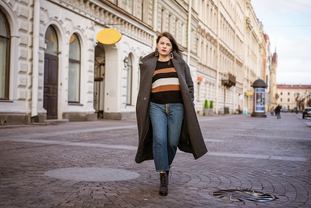 Donna felice in un cappotto che cammina per una strada cittadina