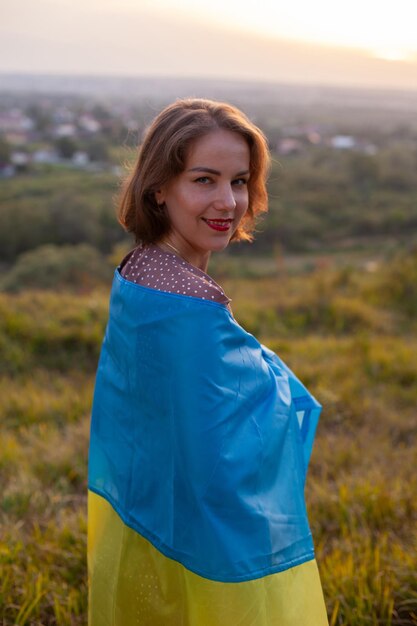 Donna felice in vestito lungo che tiene una bandiera gialla e blu dell'Ucraina