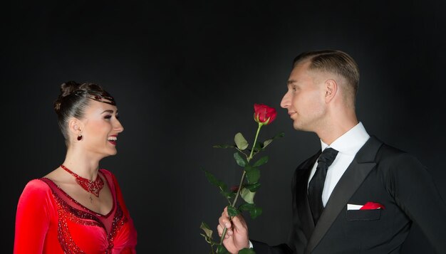 Donna felice in vestito rosso e uomo con fiore rosa