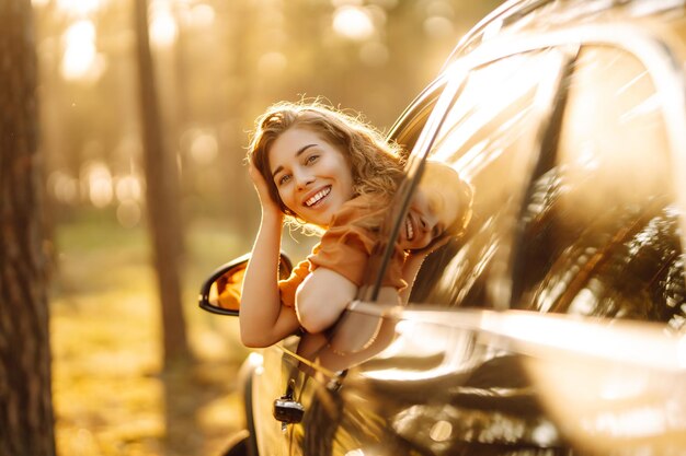 Donna felice in viaggio d'estate viaggia appoggiandosi fuori dal finestrino dell'auto Stile di vita attivo Concetto di viaggio