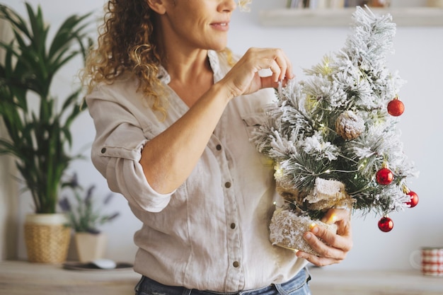 Donna felice metà sezione che decora l'albero di Natale a casa