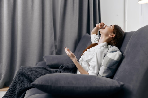 donna felice seduta sul divano con telefono cellulare e tende sullo sfondo foto di alta qualità