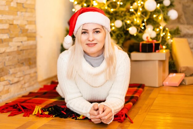 Donna felice seduta vicino all'albero di Natale a casa