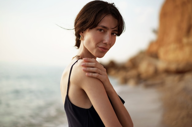 Donna felice sulla spiaggia che cammina in riva al mare