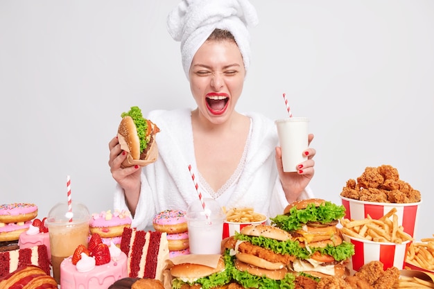 Donna felicissima che mangia un hamburger e un milskhake